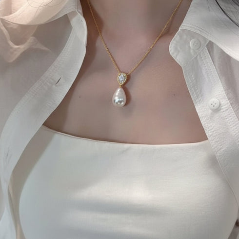 Necklace featuring a gold chain and a heart-shaped zirconia pendant above a teardrop baroque freshwater pearl.