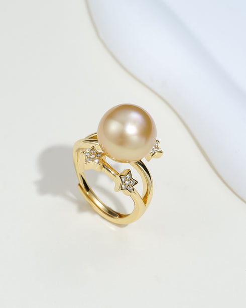 Ring with a large South Sea golden pearl on an open gold band and star-shaped cubic zirconia accents.