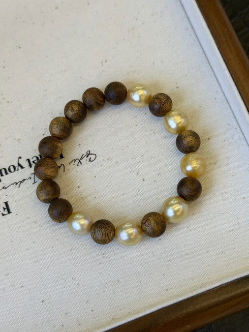 Bracelet with alternating dark wood beads and cream freshwater pearls on a white background