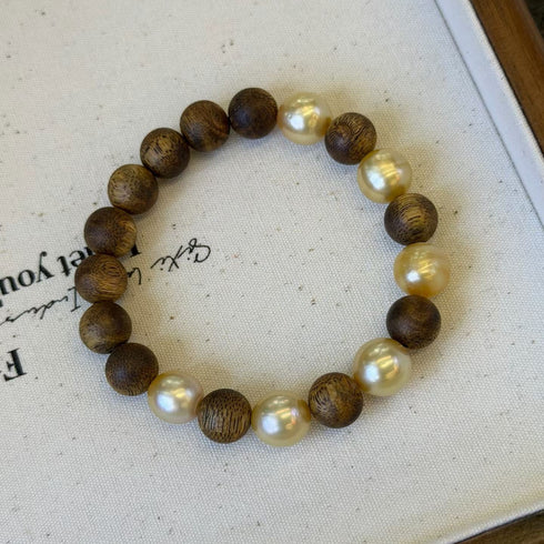 Bracelet with alternating dark wood beads and cream freshwater pearls on a white background