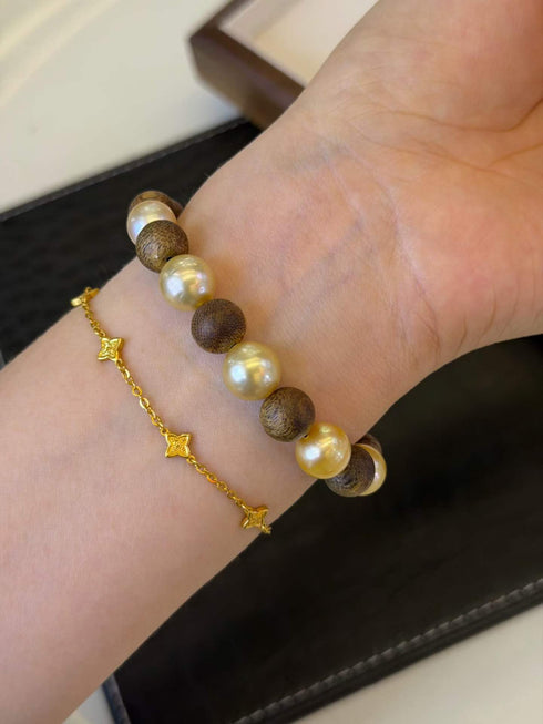 Bracelet: Aurora White Freshwater Pearl Tennis Bracelet with white pearls and brown beads, and a gold star-chain bracelet visible.