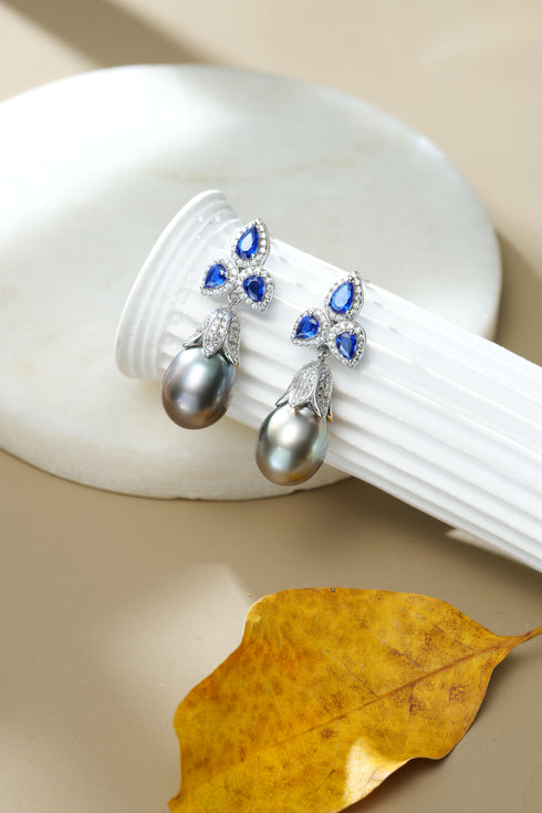 Tahitian pearl drop earrings with blue teardrop gems and diamond halos in a silver setting