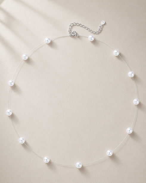 Floating pearl necklace with 5–6mm white starry freshwater pearls on a clear thread and adjustable silver extender chain