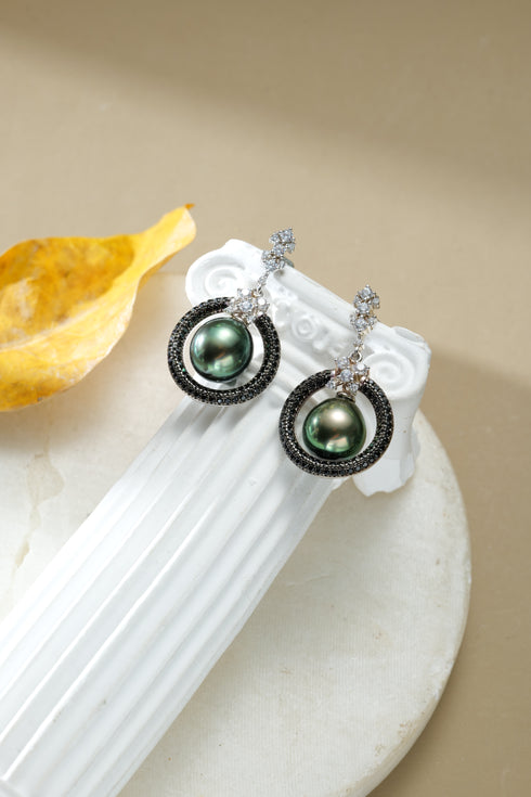 Pair of Tahitian pearl stellar drop earrings with green Tahitian pearls framed by black pave hoops and crystal accents