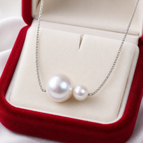 Dual freshwater pearl pendant necklace with two white pearls on a silver chain, in a cream-lined red jewelry box.