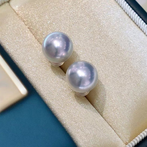 Pearl earrings in a jewelry box on a blue surface