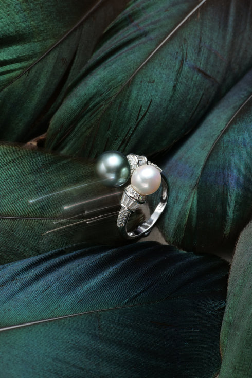 Pearl halo rings: pair featuring dark Tahitian pearl and white pearl with diamond-accent bands.
