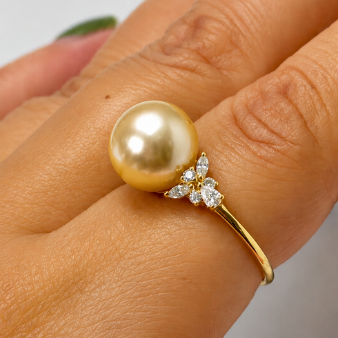Ring: 10–11mm golden South Sea pearl with a diamond-leaf cluster on a gold band.