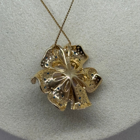 Pendant necklace with a gold-tone flower pendant and blue accent stones on a slim chain