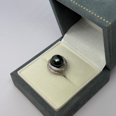 Ring: 11–12mm Tahitian pearl with ocean swirl diamond-studded band in a blue suede box.