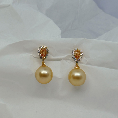 Earrings with 11–12mm golden South Sea champagne pearls, each accented by a halo of small stones on gold settings.