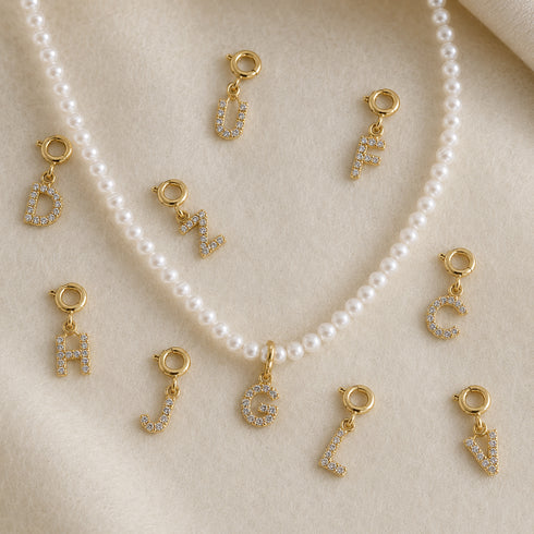 Pendants: Dainty Initial Letter Charm – Pavé Cubic Zirconia, gold-tone letter charms on a pearl necklace by House Of Pearls.