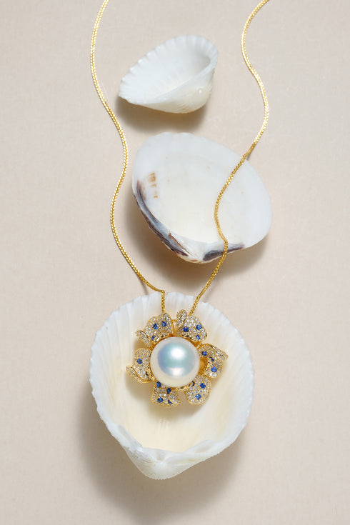 Gold-tone necklace with 10–11mm freshwater pearl in a pave blue zirconia flower pendant.
