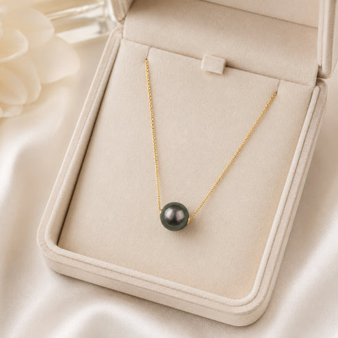 Tahitian Pearl Floating Pendant Necklace with a gold-tone chain and dark pearl in a beige jewelry box.