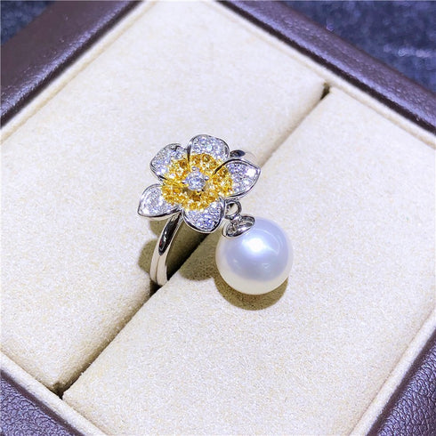 Ring with flower design, silver band, pave diamond petals, yellow center, and dangling freshwater pearl