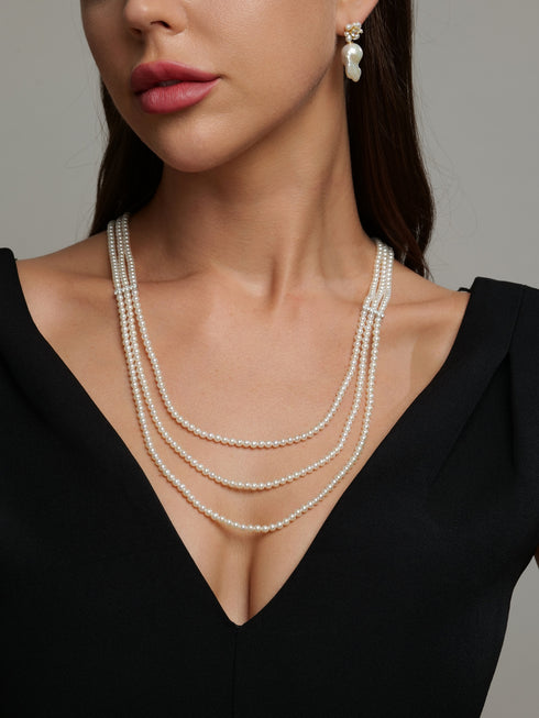 3-4mm freshwater pearl triple-layer necklace in white, draped over a black neckline.