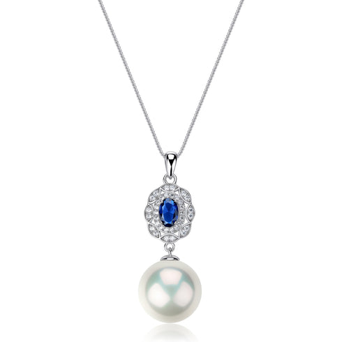 Pendant necklace with a royal blue gemstone surrounded by pavé crystals and a freshwater pearl drop on a silver chain.