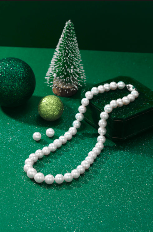 Graduated white freshwater pearl necklace by House Of Pearls; includes a pair of pearl stud earrings on green backdrop.