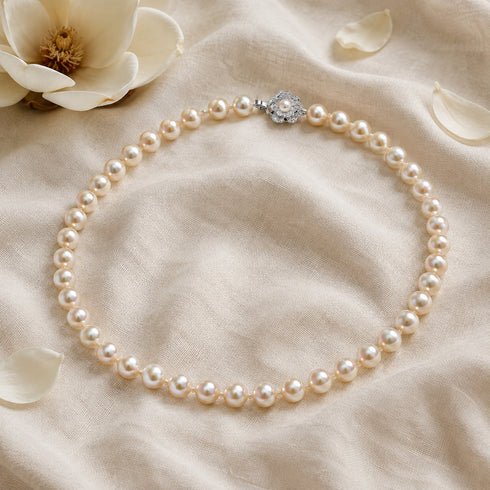 Pearl necklace with 9–10mm white freshwater pearls and a decorative silver flower clasp.