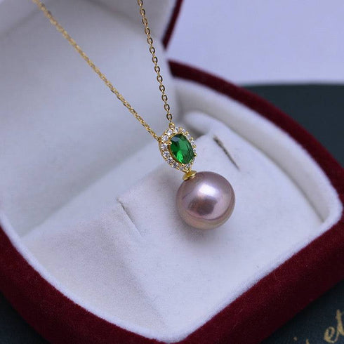 Necklace with 11–12mm freshwater pearl pendant and emerald-green gem halo on a gold chain.