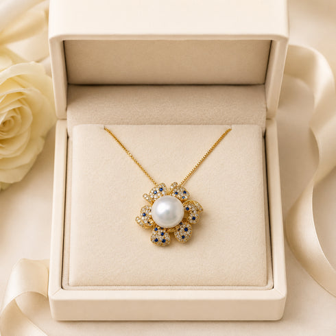 Pendant necklace with a flower-shaped gold-tone pendant, Edison pearl and blue sapphire accents on a gold chain.