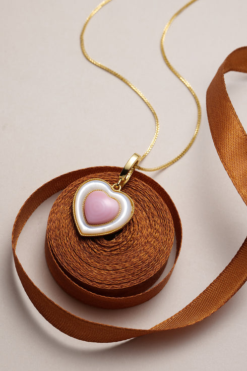 Gold-tone necklace with pink heart conch shell pendant in a white and gold bezel.