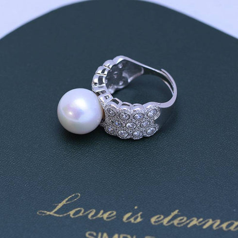 Ring with 12-13mm freshwater pearl and a large full CZ cluster on a wide silver-tone band; eye-catching, statement piece.