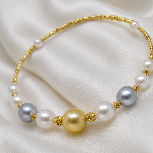 Bracelet with a gold-tone beaded band, white Akoya pearls, blue-grey pearls, and a central golden South Sea pearl.