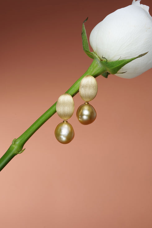 Drop earrings featuring 12–13mm Golden South Sea baroque pearls and brushed gold oval drops.
