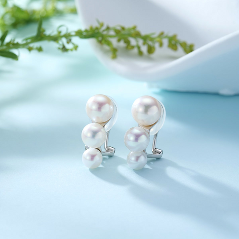 Graduated freshwater pearl trio clip-on earrings; a pair featuring three white iridescent pearls on silver clips.