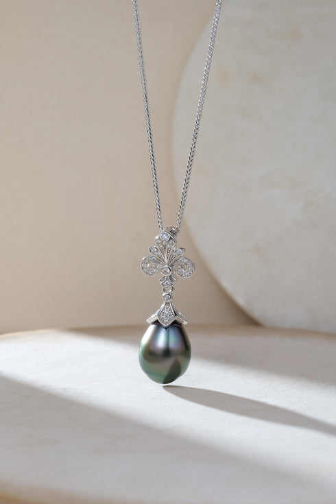 Tahitian black pearl pendant necklace with an ornate diamond-studded silver cap on a silver chain.